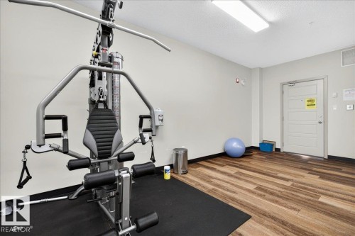 Dedicated fitness area featuring wood-finish flooring, light grey walls, and a recessed ceiling light fixture - 106 320 Ambleside Link Sw, Edmonton, AB - Indoor Photo Showing Gym Room