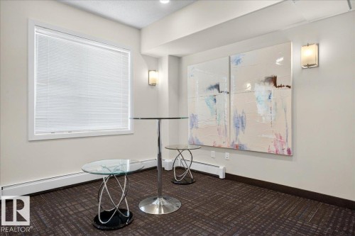 Bright window with white blinds, neutral wall paint, two wall-mounted sconces, and patterned carpet flooring - 106 320 Ambleside Link Sw, Edmonton, AB - Indoor