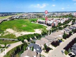 Aerial view showcasing a residential area featuring single-family homes with gray roofs and a multi-story condominium complex - 