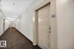 Entry door with horizontal panel design and contemporary hardware opening onto a hallway featuring patterned carpet flooring, recessed ceiling lights, and wall sconces - 