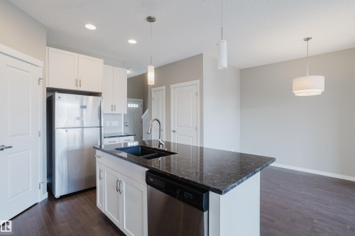 Kitchen island featuring a double basin sink, dark countertop, and integrated dishwasher - 17707 59 Street Nw, Edmonton, AB - Indoor Photo Showing Kitchen With Double Sink