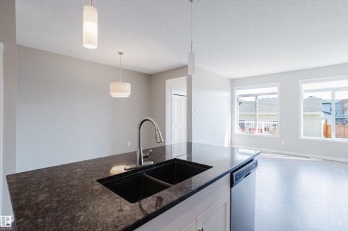 Kitchen island featuring a dark speckled countertop, undermount sink, and gooseneck faucet - 17707 59 Street Nw, Edmonton, AB - Indoor Photo Showing Kitchen With Double Sink