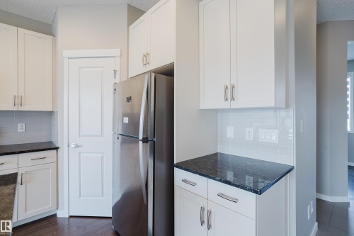 Kitchen featuring white cabinetry with brushed nickel hardware, dark speckled countertops, and a subway tile backsplash - 17707 59 Street Nw, Edmonton, AB - Indoor Photo Showing Kitchen