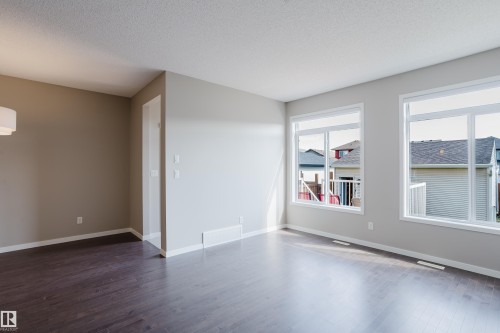 Spacious interior featuring two large windows, wood-finish flooring, and light neutral wall colors - 17707 59 Street Nw, Edmonton, AB - Indoor Photo Showing Other Room