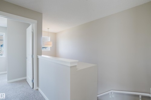 Upper-level landing with neutral wall paint and white trim, featuring a contemporary drum pendant light fixture - 17707 59 Street Nw, Edmonton, AB - Indoor Photo Showing Other Room