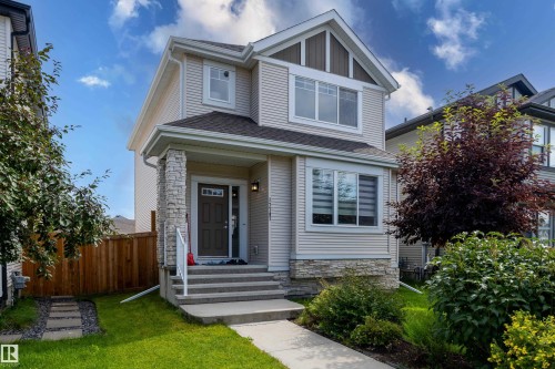 Two-story residential exterior featuring light-colored horizontal siding, a stone veneer accent, and an asphalt shingle roof - 17707 59 Street Nw, Edmonton, AB - Outdoor