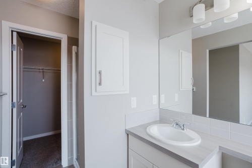 Bathroom vanity featuring a white oval sink, chrome faucet, and a large wall-mounted mirror - 17707 59 Street Nw, Edmonton, AB - Indoor Photo Showing Bathroom