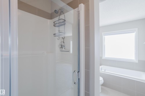 Glass-enclosed shower with a chrome shower head and light-toned tile detailing - 17707 59 Street Nw, Edmonton, AB - Indoor Photo Showing Bathroom