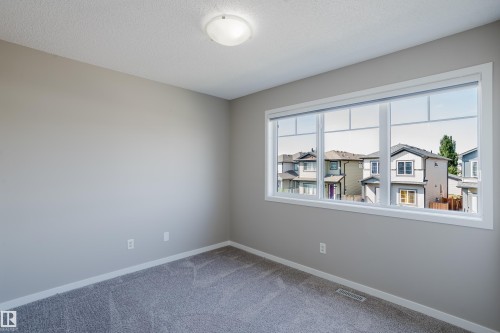 Bright room featuring a large, multi-pane window with white trim, soft gray walls, and plush gray carpeting - 17707 59 Street Nw, Edmonton, AB - Indoor Photo Showing Other Room