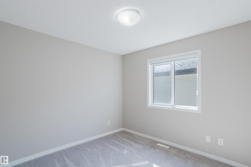 Neutral-toned room featuring a single window with white trim, light grey carpeting, and a flush-mount ceiling light fixture - 17707 59 Street Nw, Edmonton, AB - Indoor Photo Showing Other Room