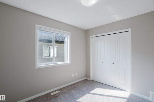 Room featuring neutral grey wall paint, grey carpet flooring, and a white bi-fold closet - 17707 59 Street Nw, Edmonton, AB - Indoor