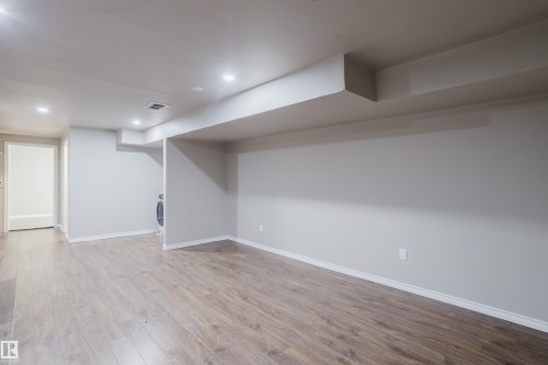 Spacious room featuring wood-finish flooring, recessed lighting, neutral wall paint, and white trim - 17707 59 Street Nw, Edmonton, AB - Indoor