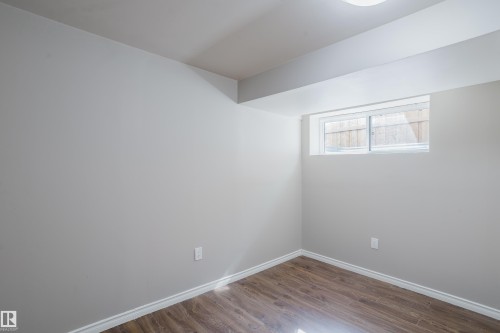Room featuring light gray walls, wood-finish flooring, white baseboards, and a window - 17707 59 Street Nw, Edmonton, AB - Indoor Photo Showing Other Room