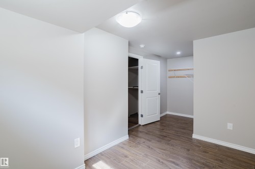 Neutral-toned room featuring wood-finish flooring, white baseboards, and a flush-mount ceiling light - 17707 59 Street Nw, Edmonton, AB - Indoor Photo Showing Other Room