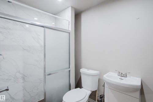 Shower enclosure featuring a sliding frosted glass door and white marbled wall tiling - 17707 59 Street Nw, Edmonton, AB - Indoor Photo Showing Bathroom