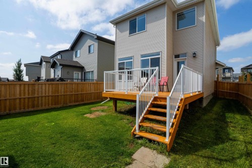 Rear exterior featuring a wooden deck with white railings, a direct walk-out to the lawn, and a privacy fence - 17707 59 Street Nw, Edmonton, AB - Outdoor
