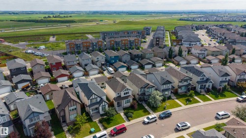 Aerial perspective showcasing a residential community with varied architectural styles, green spaces, and a paved street network - 17707 59 Street Nw, Edmonton, AB - Outdoor With View