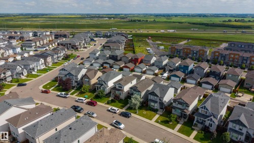 Aerial perspective showcasing a residential development with diverse architectural styles, landscaped front yards, and paved streets - 17707 59 Street Nw, Edmonton, AB - Outdoor With View