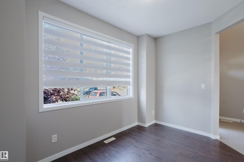 Bright room featuring a large window with privacy blinds, wood-finish flooring, light gray wall paint, and white baseboards - 17707 59 Street Nw, Edmonton, AB - Indoor Photo Showing Other Room