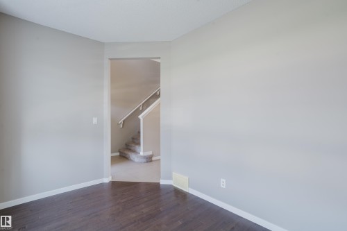 Dark wood-finish flooring with light gray walls and white trim - 17707 59 Street Nw, Edmonton, AB - Indoor Photo Showing Other Room