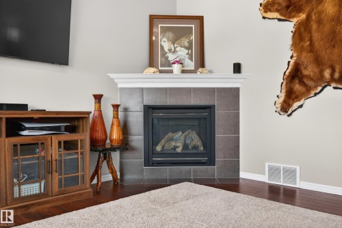 Corner fireplace with gray tile surround, white mantel, and black gas insert - 9 Snowbird Crescent, Leduc, AB - Indoor Photo Showing Living Room With Fireplace