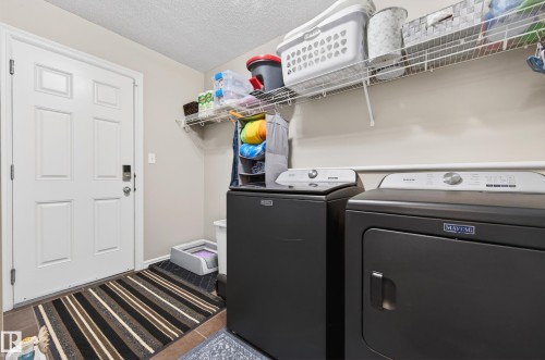 Dedicated laundry area featuring a white six-panel door, neutral wall paint, and overhead wire shelving - 9 Snowbird Crescent, Leduc, AB - Indoor Photo Showing Laundry Room