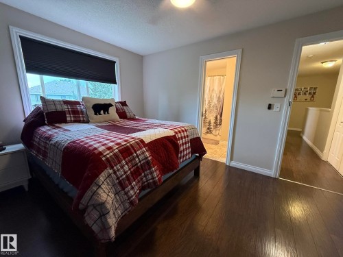 Bedroom featuring wood-finish flooring and a large window with privacy blinds - #93 12050 17 Av Sw, Edmonton, AB - Indoor Photo Showing Bedroom