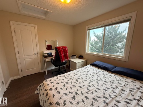 Bedroom featuring wood-finish flooring, a double-paned window with white trim, and a textured ceiling - #93 12050 17 Av Sw, Edmonton, AB - Indoor Photo Showing Bedroom