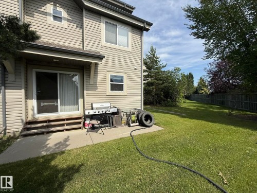 Rear exterior featuring horizontal siding, a ground-level concrete patio, and a sliding glass door with a screen - #93 12050 17 Av Sw, Edmonton, AB - Outdoor With Deck Patio Veranda