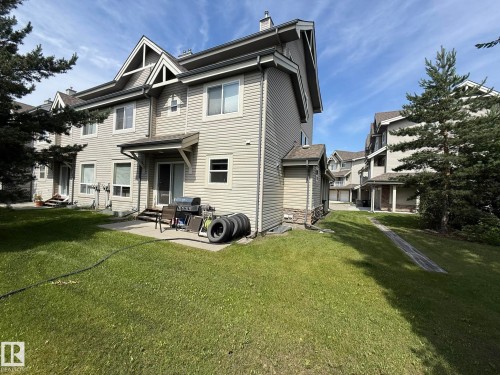 Rear exterior featuring neutral-toned siding and multiple windows - #93 12050 17 Av Sw, Edmonton, AB - Outdoor