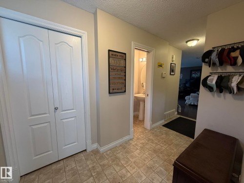 Entryway featuring neutral wall paint, tiled flooring, white bi-fold doors, and a pedestal sink in the powder room - #93 12050 17 Av Sw, Edmonton, AB - Indoor Photo Showing Other Room