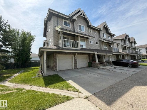 Contemporary townhouse exterior featuring gray siding, stone accents, and multiple gabled rooflines - #93 12050 17 Av Sw, Edmonton, AB - Outdoor With Facade