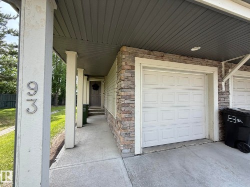Exterior featuring a single garage door, stone veneer accents, and a covered entry - #93 12050 17 Av Sw, Edmonton, AB - Outdoor With Exterior