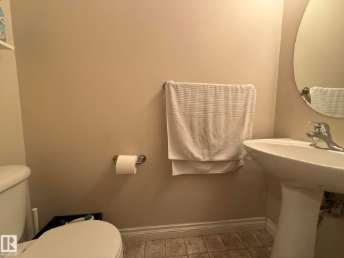 Pedestal sink with chrome faucet, complemented by an oval wall mirror - #93 12050 17 Av Sw, Edmonton, AB - Indoor Photo Showing Bathroom