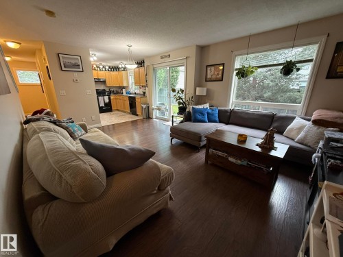 Open-concept living area featuring wood-finish flooring and a large picture window - #93 12050 17 Av Sw, Edmonton, AB - Indoor Photo Showing Living Room