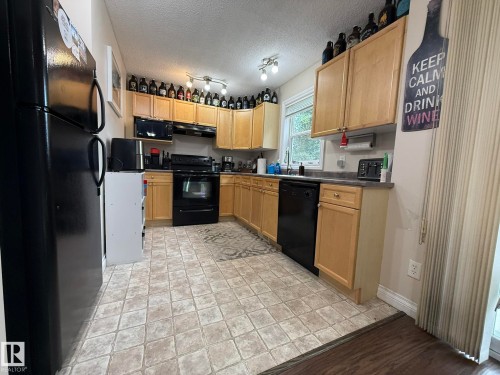 Kitchen featuring light wood cabinetry, black appliances, and a window above the sink - #93 12050 17 Av Sw, Edmonton, AB - Indoor Photo Showing Kitchen