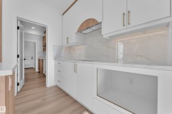 White cabinetry featuring gold-tone hardware, wood-finish accents, and a stone-finish countertop - 