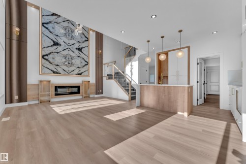 Open-concept living space featuring wood-finish flooring and a central island with a light-toned countertop - 382 Linden Loop, Leduc, AB - Indoor With Fireplace