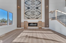 Vaulted ceiling living space featuring a contemporary fireplace with a large decorative panel, recessed electric fireplace, and light wood-finish flooring - 