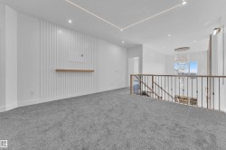 Loft space featuring plush grey carpeting, a modern accent wall with a floating wood shelf, and recessed lighting - 