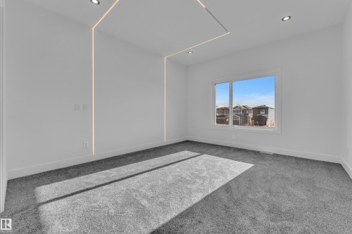Spacious room featuring modern recessed lighting, integrated wall and ceiling strip lighting, a large window, white baseboards, and gray carpet - 382 Linden Loop, Leduc, AB - Indoor Photo Showing Other Room