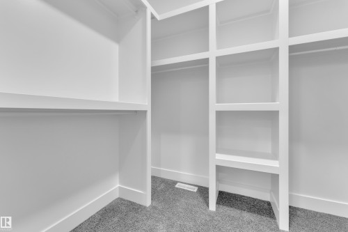 Built-in closet system featuring white shelving and hanging rods - 382 Linden Loop, Leduc, AB - Indoor With Storage