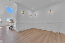 Open-concept room featuring light wood-finish flooring, white wainscoting, and recessed lighting - 