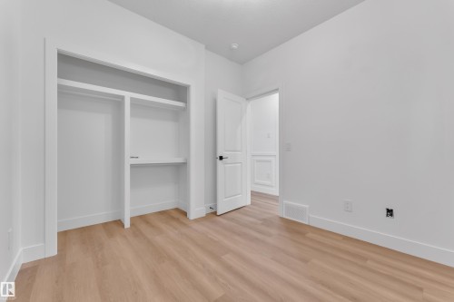 Room featuring wood-finish flooring, white walls, and a recessed closet with shelving and hanging rods - 382 Linden Loop, Leduc, AB - Indoor Photo Showing Other Room