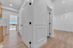 Open corridor featuring wood-finish flooring, recessed lighting, and crisp white paneled walls - 