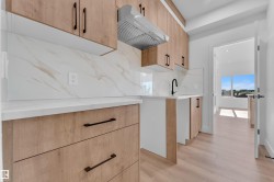 Modern kitchen with light wood-finish cabinetry and matte black hardware - 