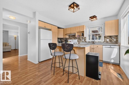 Kitchen featuring wood-finish flooring, light-toned cabinetry, and a multi-tone tile backsplash - 17411 90 Street Nw, Edmonton, AB - Indoor Photo Showing Kitchen