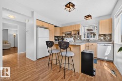 Kitchen featuring wood-finish flooring, light-toned cabinetry, and a multi-tone tile backsplash - 