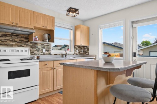 Kitchen featuring wood-finish cabinetry, a mosaic tile backsplash, and light-toned countertops - 17411 90 Street Nw, Edmonton, AB - Indoor Photo Showing Kitchen