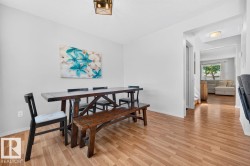 Dining area featuring light wood-finish flooring, white walls, and a contemporary ceiling light fixture - 